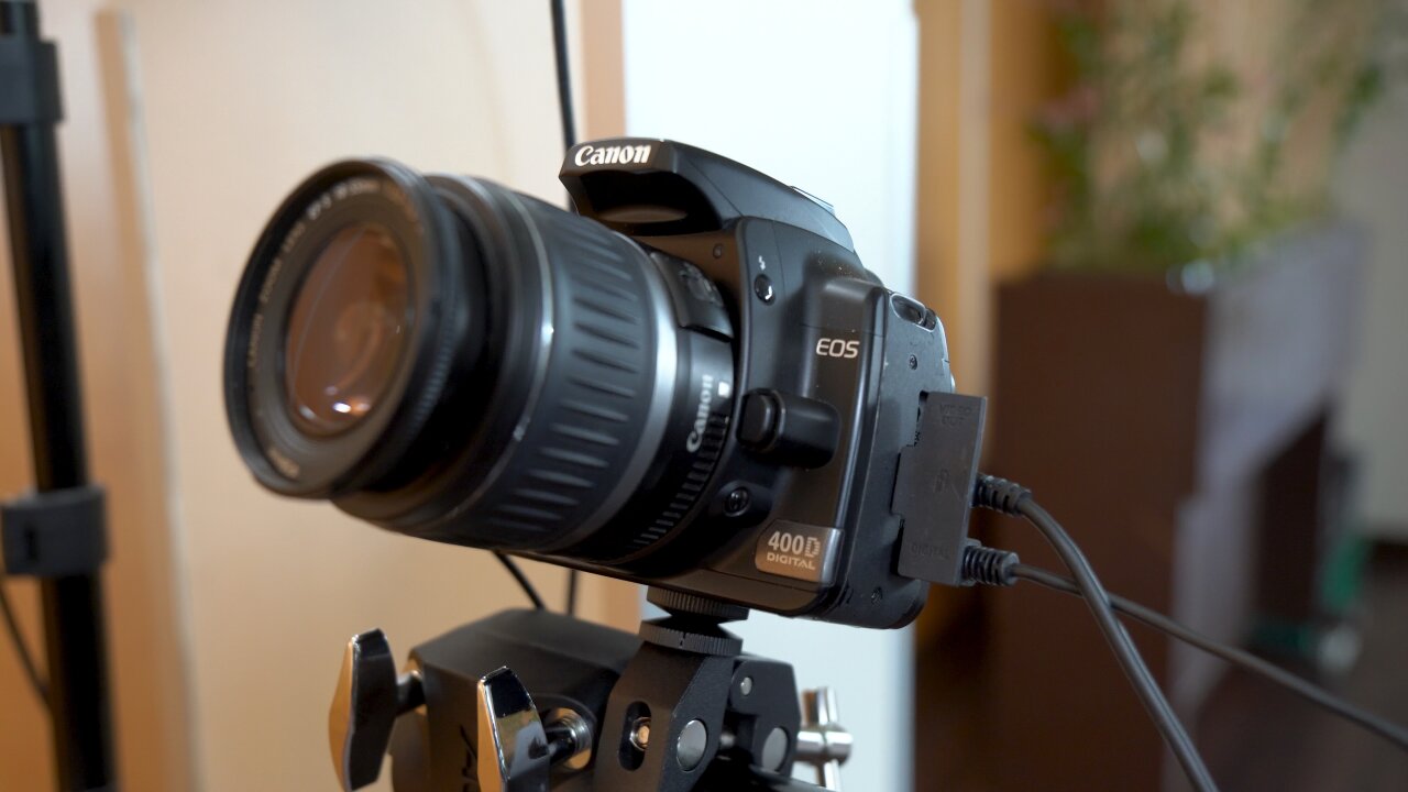 Detail shot of a Canon EOS 400d, which is mounted to two threaded plates and a clamp, which in turn is attached to the rack. One of the plates shows a crack.