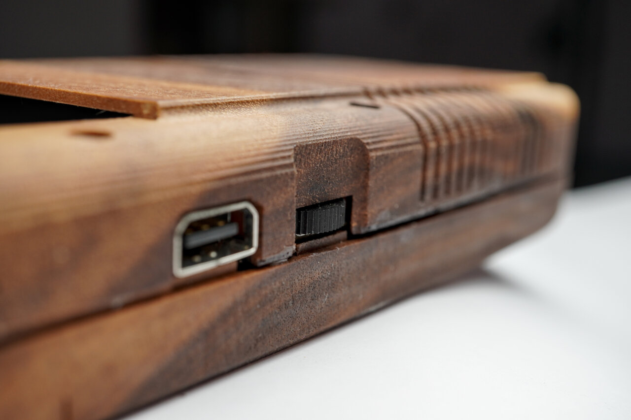 Detail photo of the right side of the wooden Game Boy near the volume control and link cable slot. A small gap is visible as well as residue from wood glue.