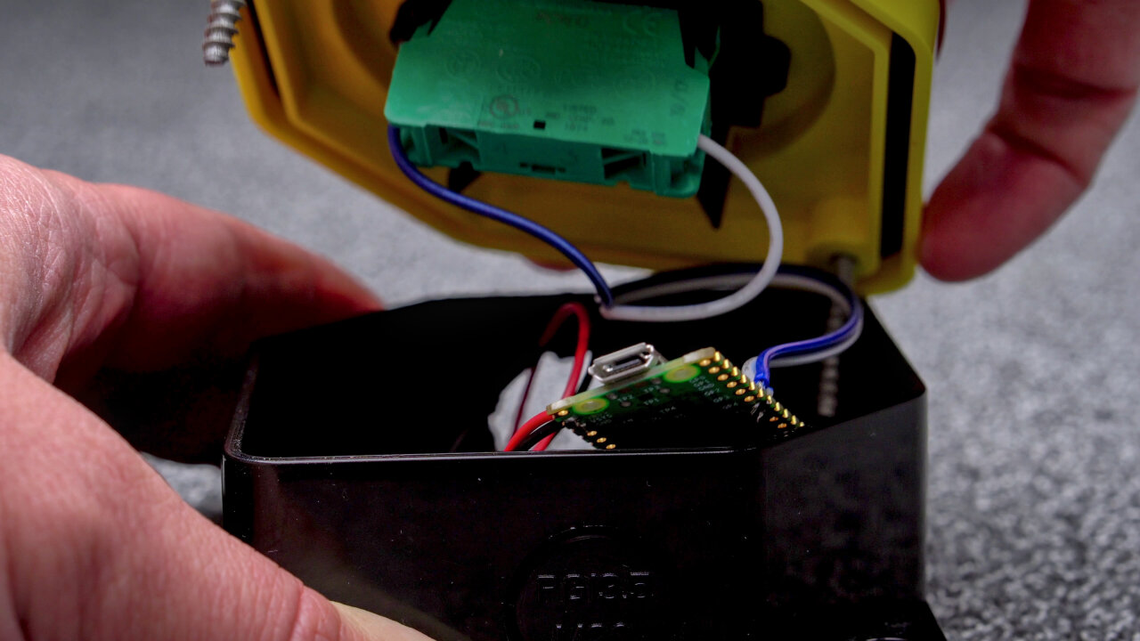 The top of one of the push buttons is lifted to reveal its insides. The edge of a Raspberry Pi Pico W is visible at the edge.